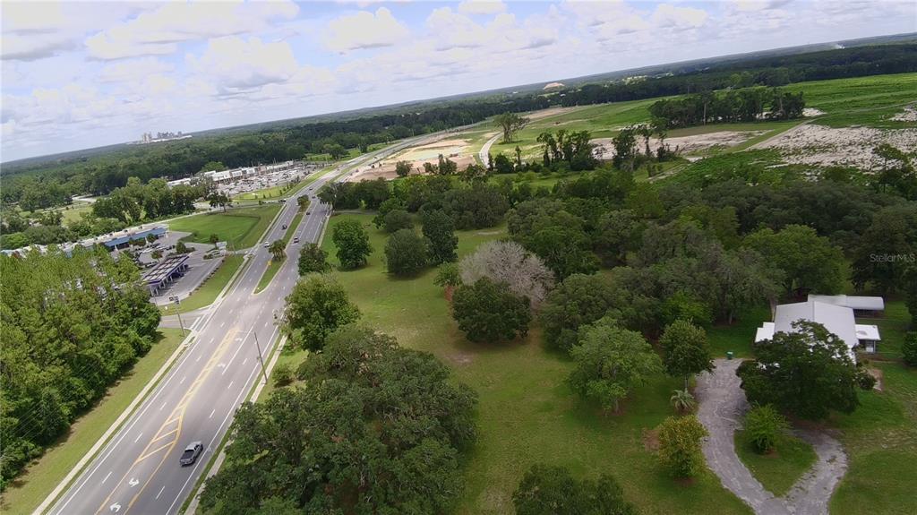 An aerial view shows a road running alongside a grassy lot with trees and a house — 24206 DOC KARELAS DRIVE, NEWBERRY, FL
