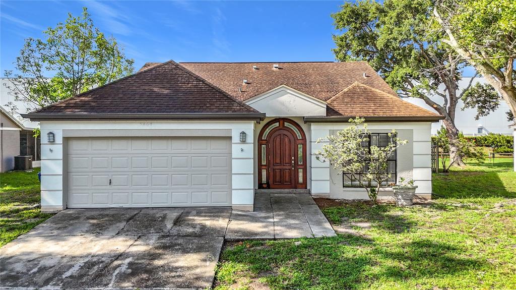 A single-story house with a brown shingled roof, white stucco walls, and a wooden front door — 5664 25TH STREET CIRCLE E, BRADENTON, FL
