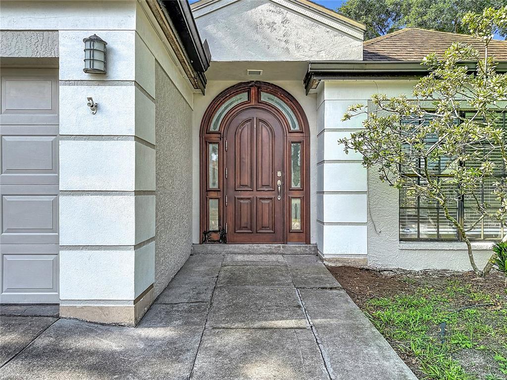 The exterior of a house features a wooden arched front door and a concrete walkway — 5664 25TH STREET CIRCLE E, BRADENTON, FL