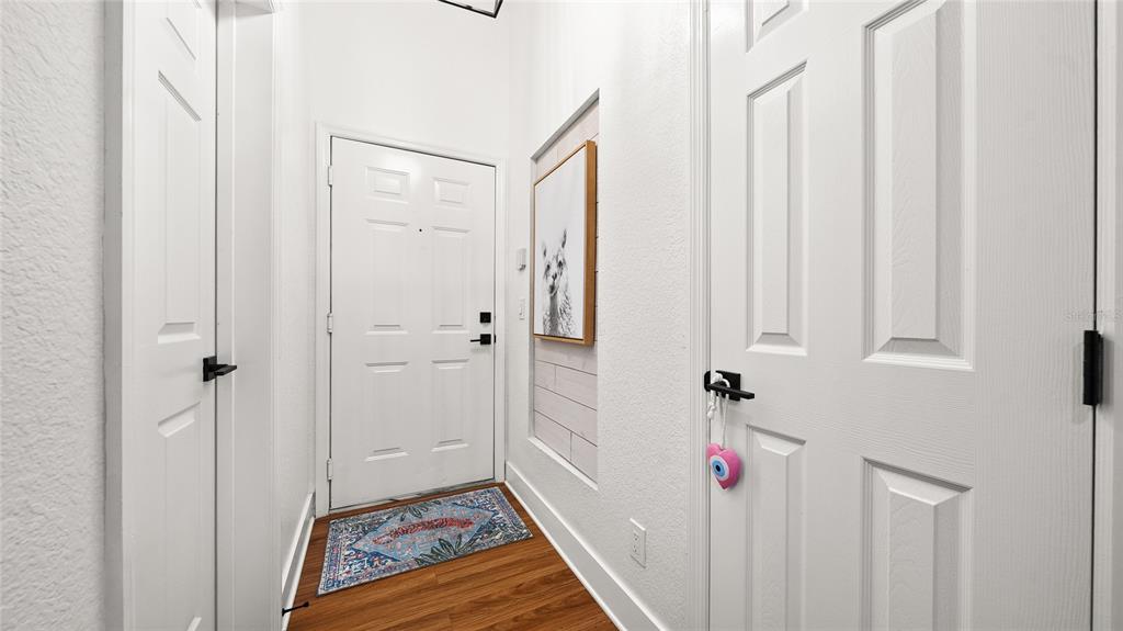 A white front door opens into a narrow entryway with wood flooring and a wall accent — 13810 SUTTON PARK DRIVE N UNIT 1433, JACKSONVILLE, FL