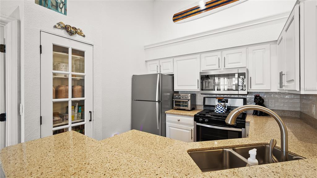 A kitchen features white cabinets, granite countertops, stainless steel appliances, and a glass-paned pantry door — 13810 SUTTON PARK DRIVE N UNIT 1433, JACKSONVILLE, FL