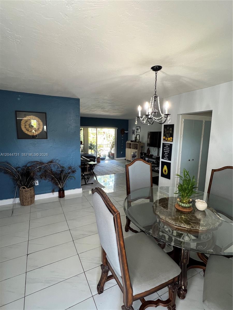 A dining area with a glass table and chandelier opens into a living room — 6900 N Kendall Dr # A205, Pinecrest FL 33156, PINECREST, FL