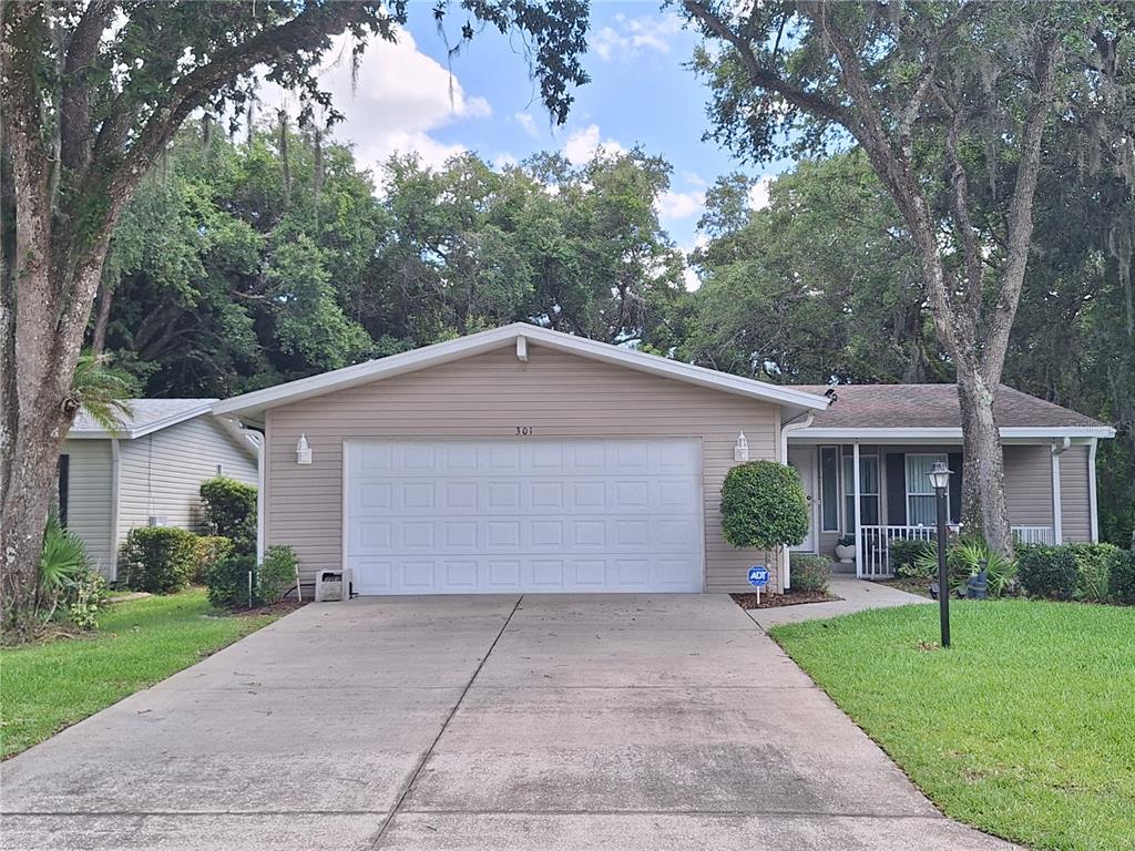 A single-story house with tan siding, a two-car garage, and a concrete driveway — 301 WATER LANDING DRIVE, OAK HILL, FL