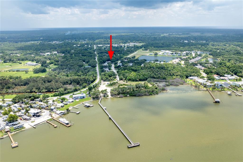 An aerial view shows a long pier extending into a lake near a residential area — 301 WATER LANDING DRIVE, OAK HILL, FL
