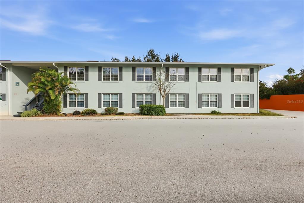 A two-story apartment building with light green siding and dark shutters under a blue sky — 4888 CONWAY ROAD UNIT 70, ORLANDO, FL