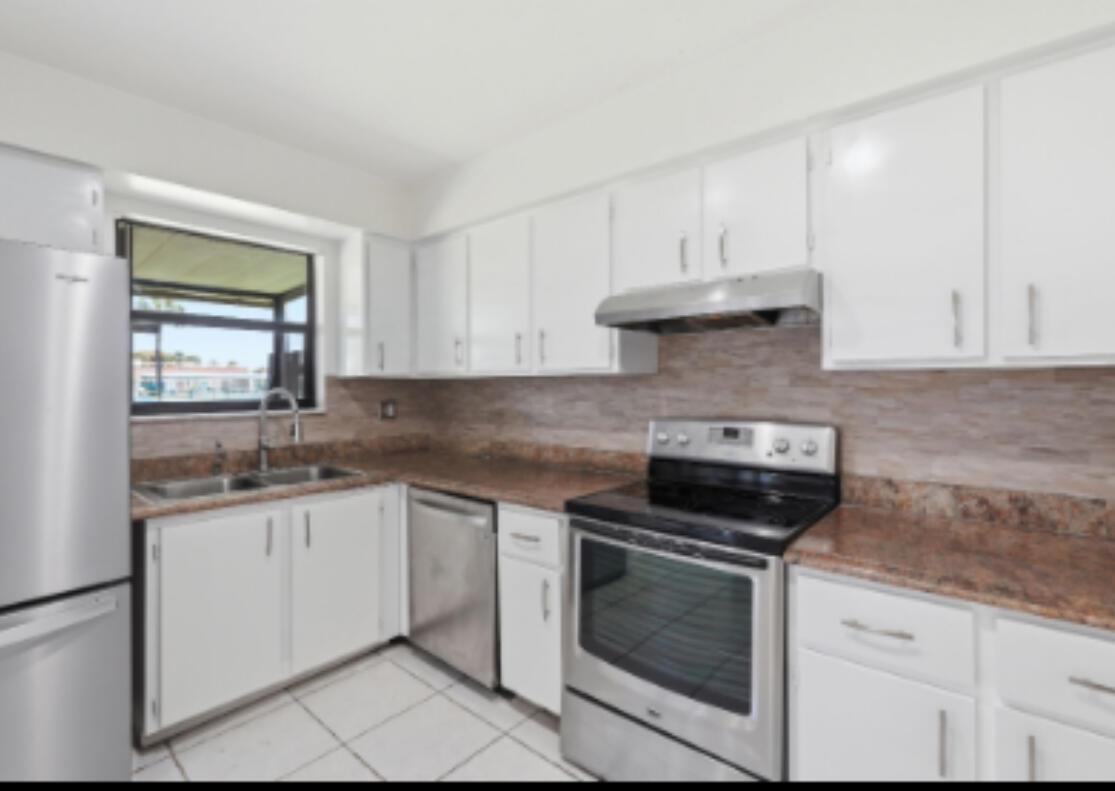A kitchen with white cabinets, stainless steel appliances, granite countertops, and a tiled backsplash — 4901 Pier Drive, FL 33463, FL
