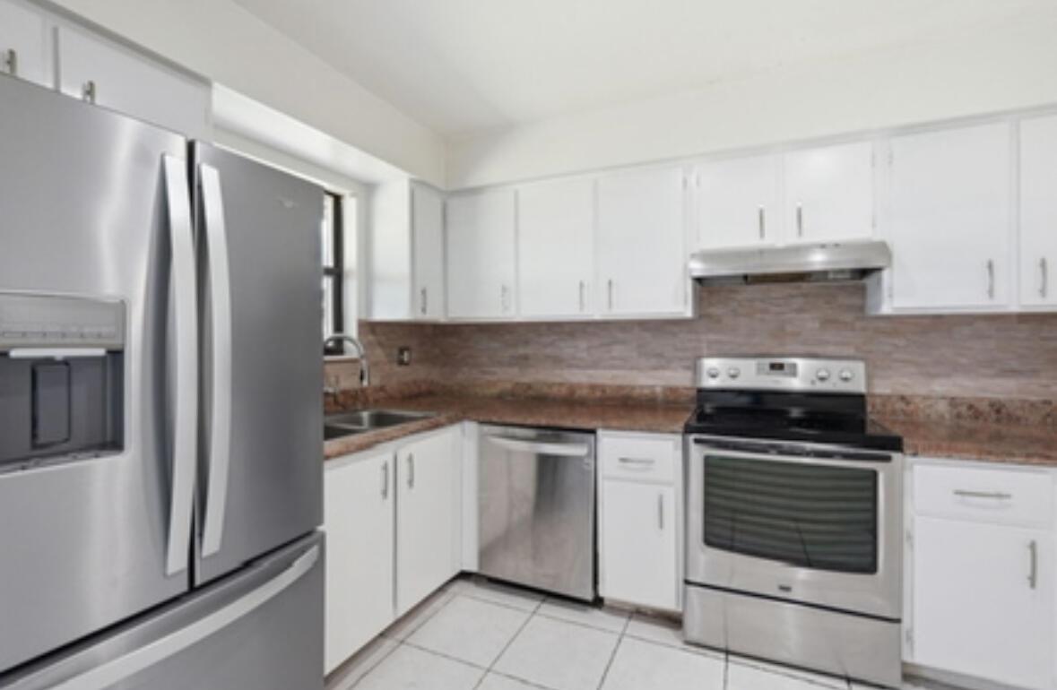 A kitchen with white cabinets, stainless steel appliances, and brown countertops — 4901 Pier Drive, FL 33463, FL