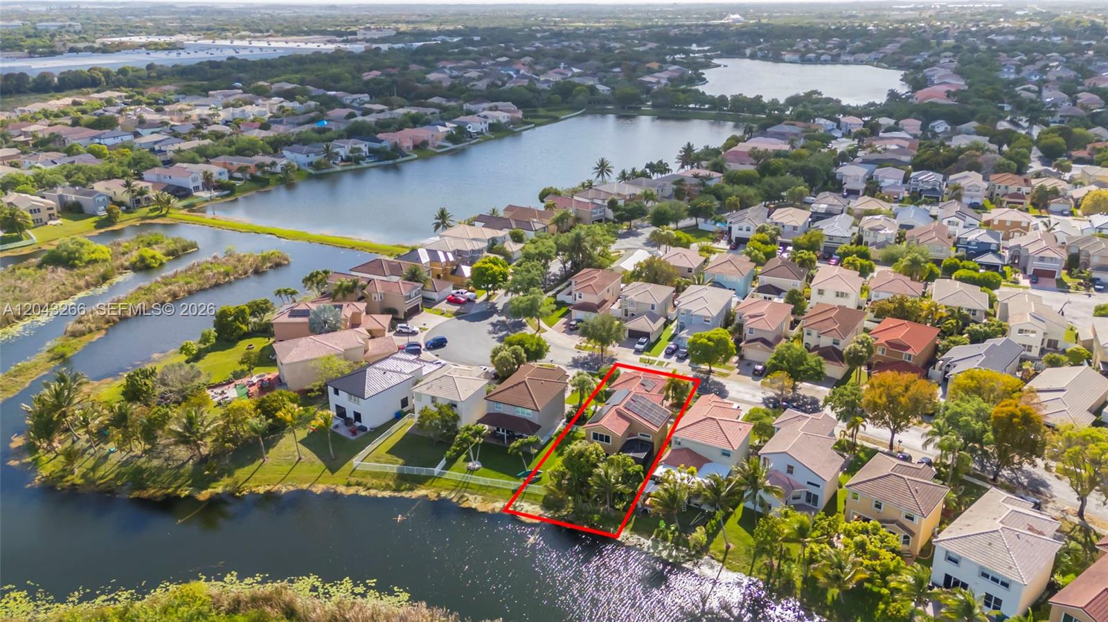 An aerial view shows a residential house with solar panels on its roof by a lake — 1941 SW 148th way, Miramar FL 33027, MIRAMAR, FL