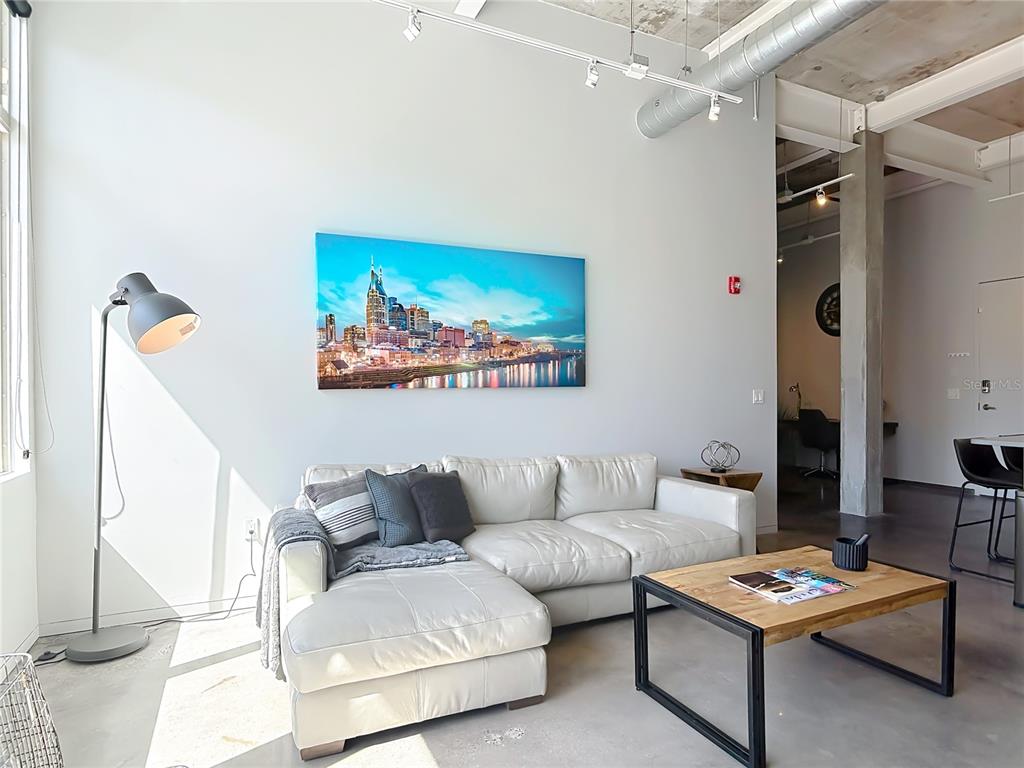 A living room features a white sectional sofa, a wooden coffee table, and city skyline art — 302 SE BROADWAY STREET UNIT 240, OCALA, FL