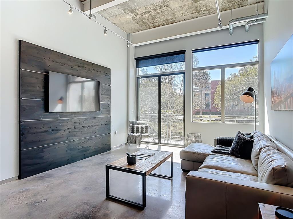 A modern living room features a dark wood accent wall, concrete floors, and large windows — 302 SE BROADWAY STREET UNIT 240, OCALA, FL