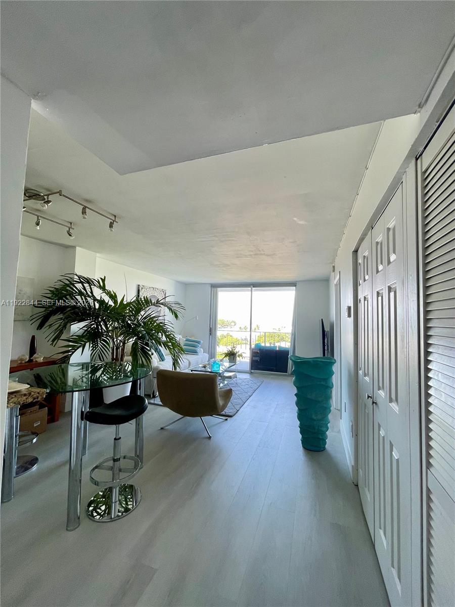 A living room features light wood flooring, a glass dining table, and a balcony view — 6900 Bay Dr # 7A, Miami Beach FL 33141, MIAMI BEACH, FL