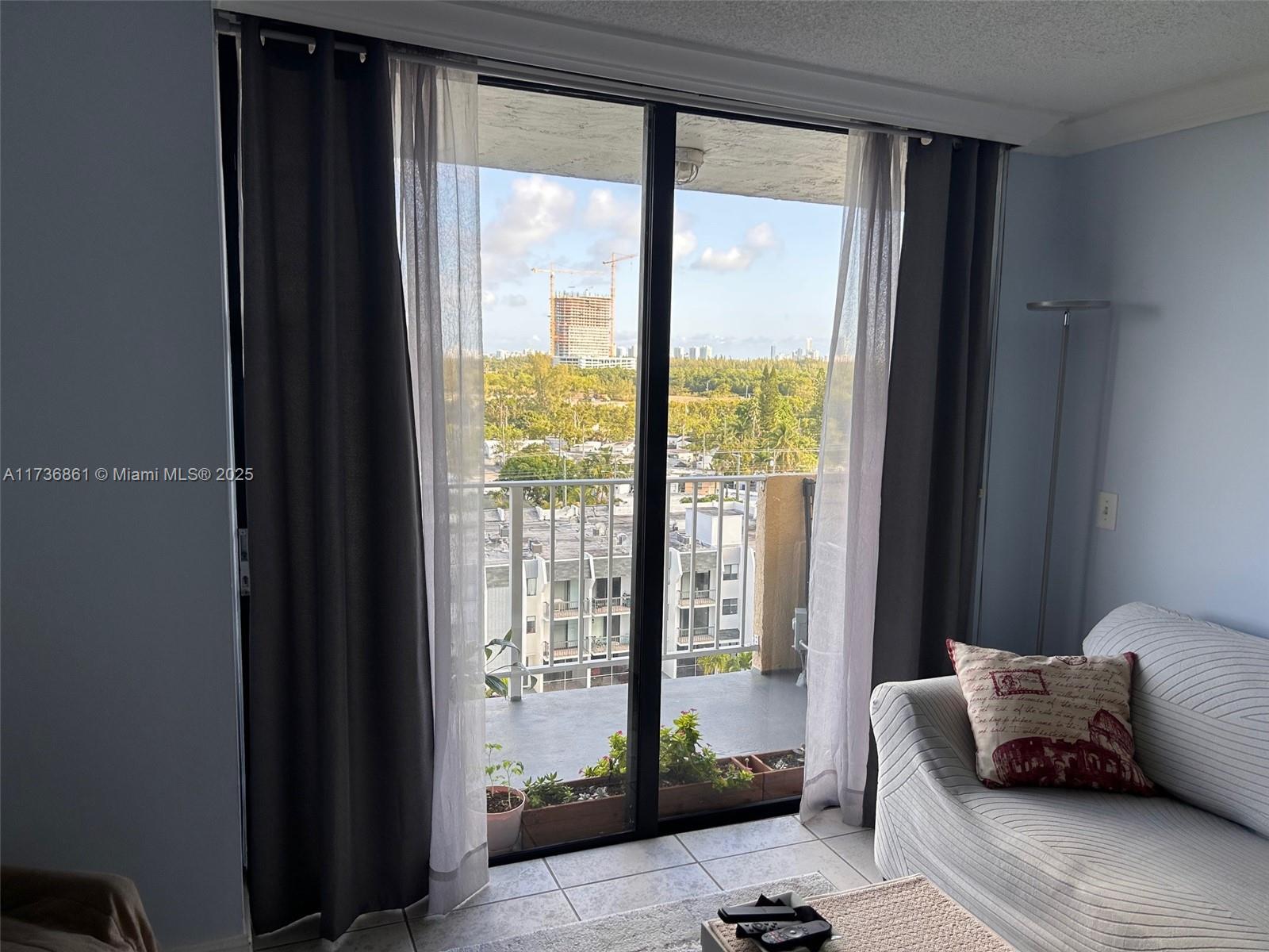 A living room features a sliding glass door leading to a balcony with city views — 2350 NE 135th St # 903, North Miami FL 33181, NORTH MIAMI, FL