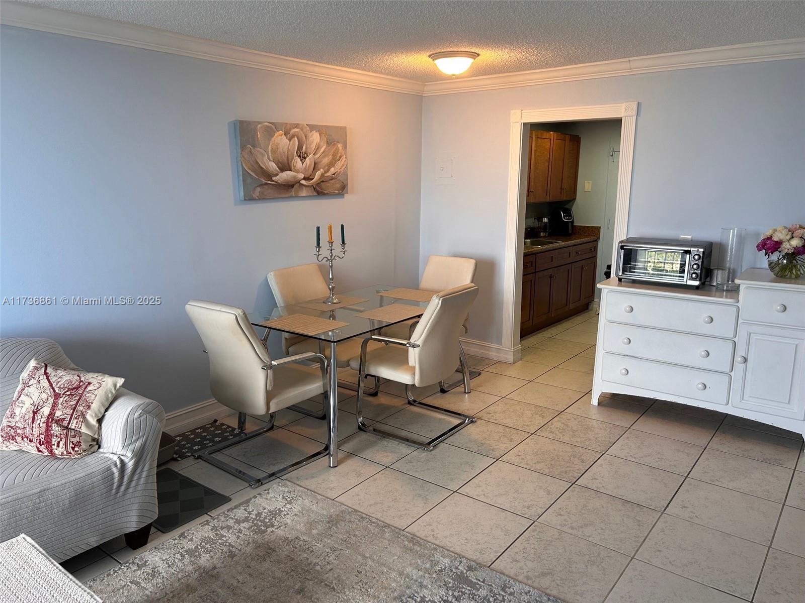 A dining area with a glass table, four chairs, and a white dresser on tile floors — 2350 NE 135th St # 903, North Miami FL 33181, NORTH MIAMI, FL