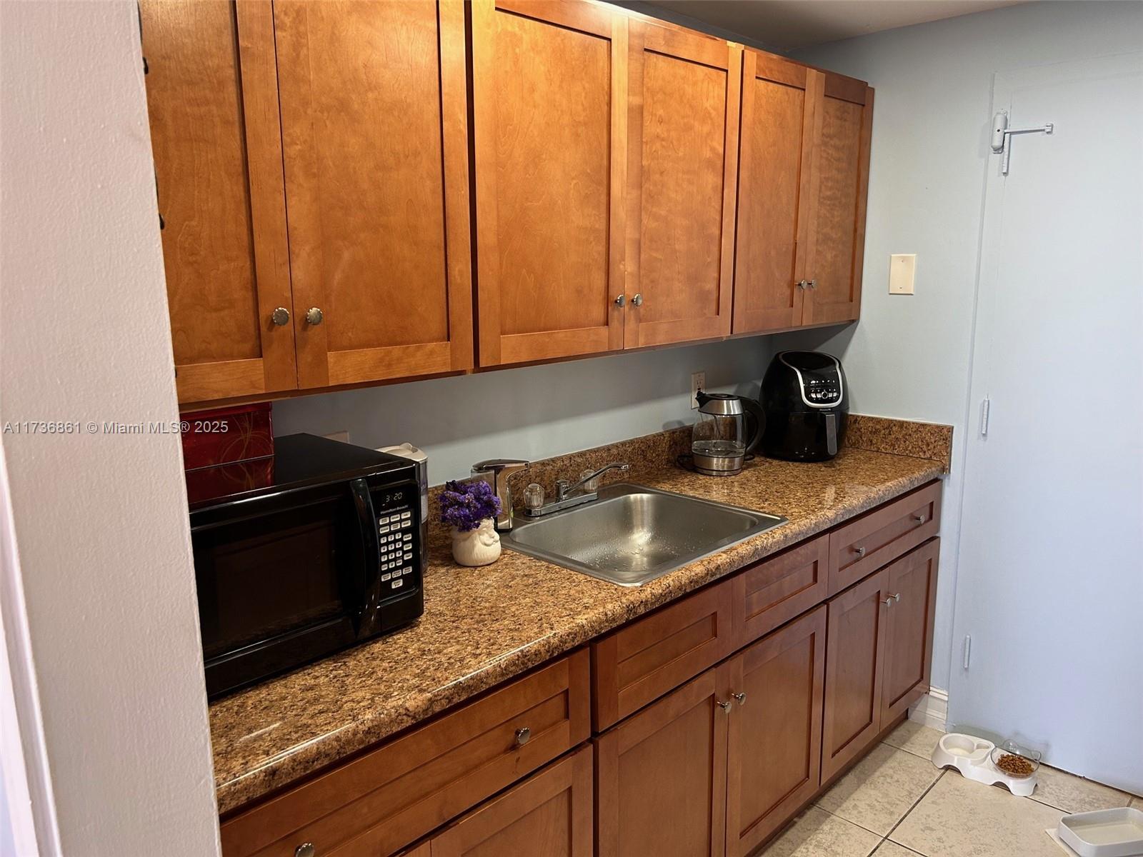 A kitchen features wood cabinets, granite countertops, a stainless steel sink, and a microwave — 2350 NE 135th St # 903, North Miami FL 33181, NORTH MIAMI, FL