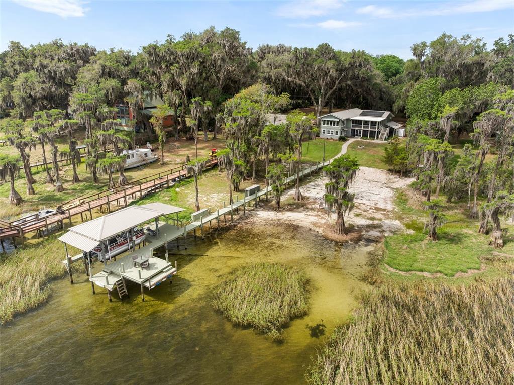 An aerial view of a waterfront property featuring a dock, boat lift, and two houses — 8026 NE 221ST STREET, MELROSE, FL
