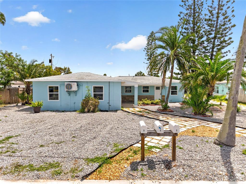 A light blue, single-story house with a gravel yard and three mailboxes in front — 14013 MARGUERITE DRIVE, MADEIRA BEACH, FL