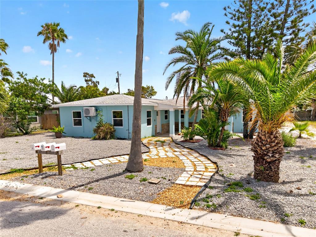 A light blue, single-story house features a stone walkway and palm trees in the yard — 14013 MARGUERITE DRIVE, MADEIRA BEACH, FL