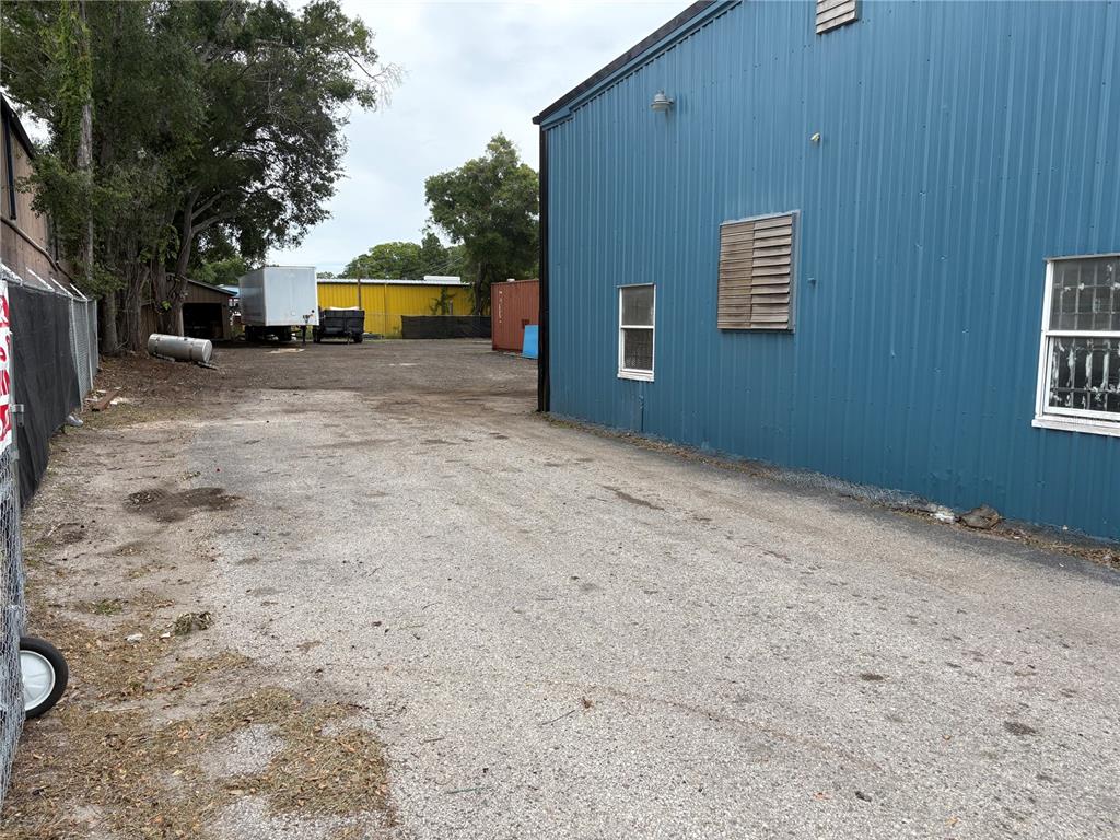 A gravel lot sits beside a blue metal industrial building with two windows — 6901 BENJAMIN ROAD, TAMPA, FL