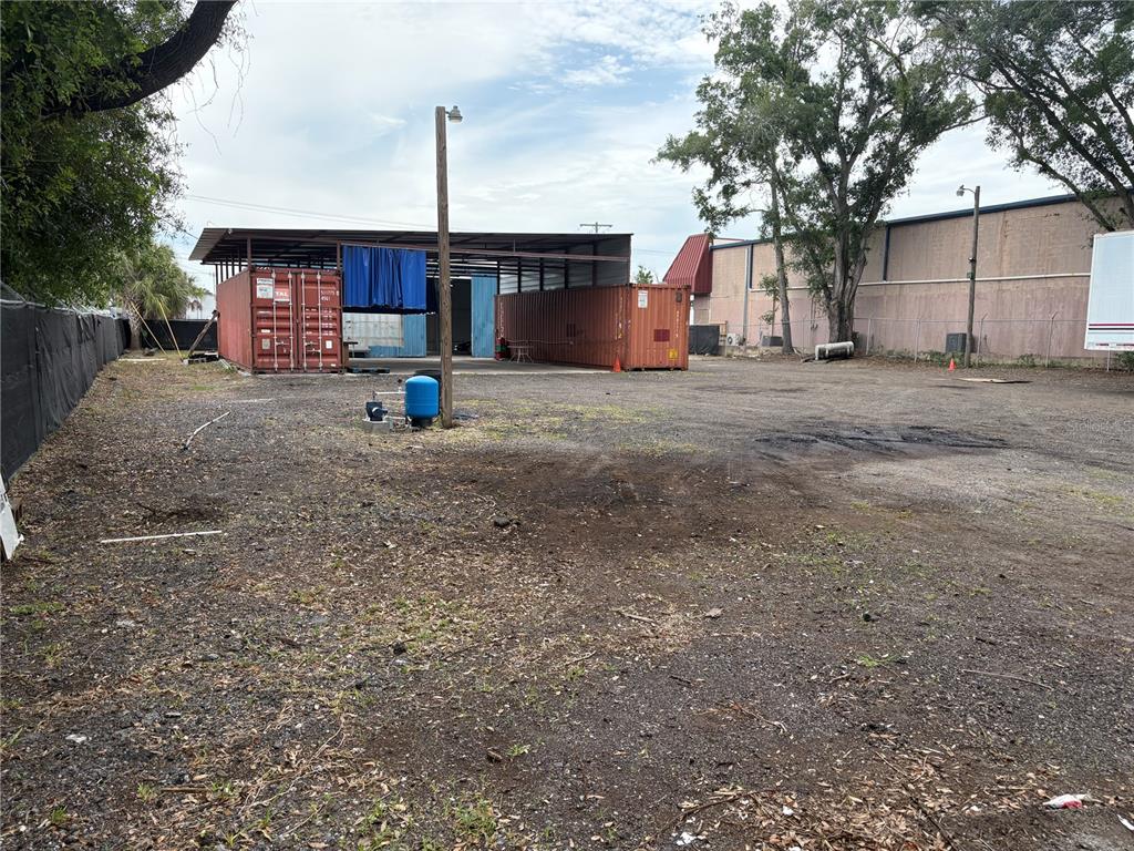 An outdoor industrial lot features two shipping containers under a metal roof structure — 6901 BENJAMIN ROAD, TAMPA, FL