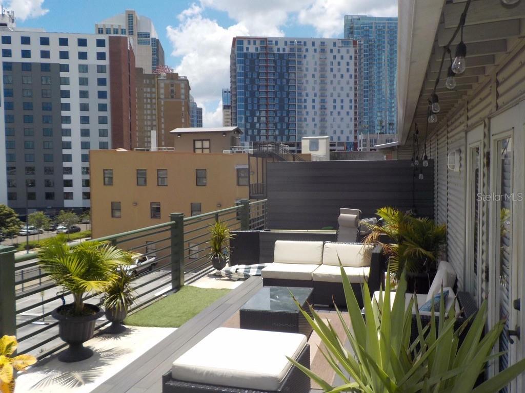 A rooftop terrace features outdoor furniture, potted plants, and views of surrounding city buildings — 1229 N FRANKLIN STREET UNIT J, TAMPA, FL