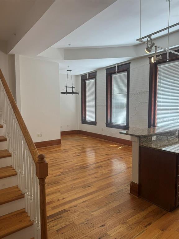 An interior view showing a living area with hardwood floors, a staircase, and large windows — 1229 N FRANKLIN STREET UNIT J, TAMPA, FL