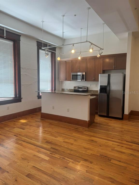 A kitchen with wooden cabinets, stainless steel appliances, and a breakfast bar on hardwood floors — 1229 N FRANKLIN STREET UNIT J, TAMPA, FL