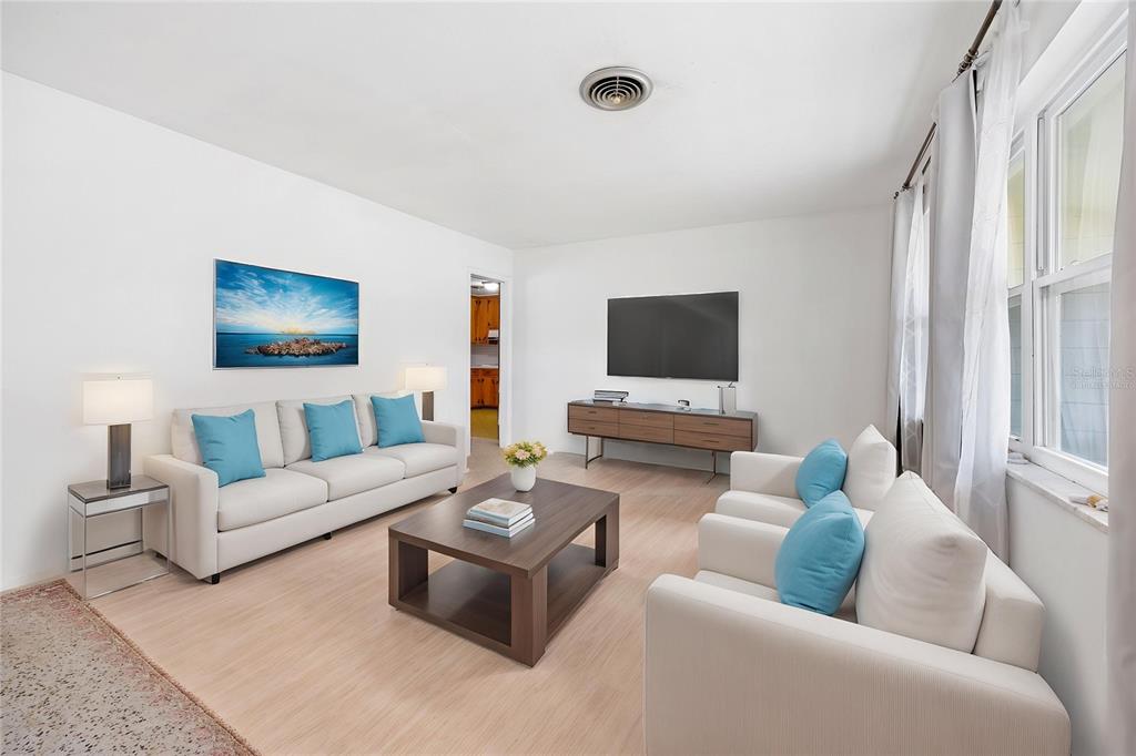 A living room features a white sofa, two armchairs, a coffee table, and a wall-mounted television — 4961 COUNTY ROAD 114, WILDWOOD, FL