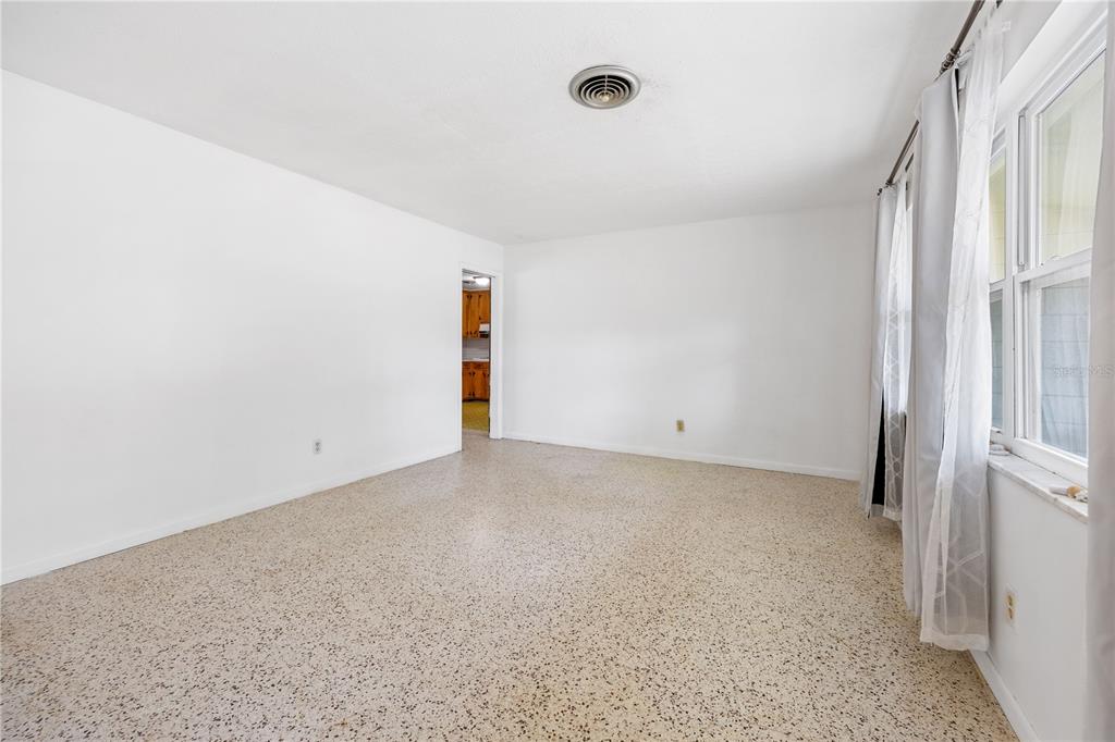 An empty room with white walls, a speckled terrazzo floor, and a ceiling air vent — 4961 COUNTY ROAD 114, WILDWOOD, FL