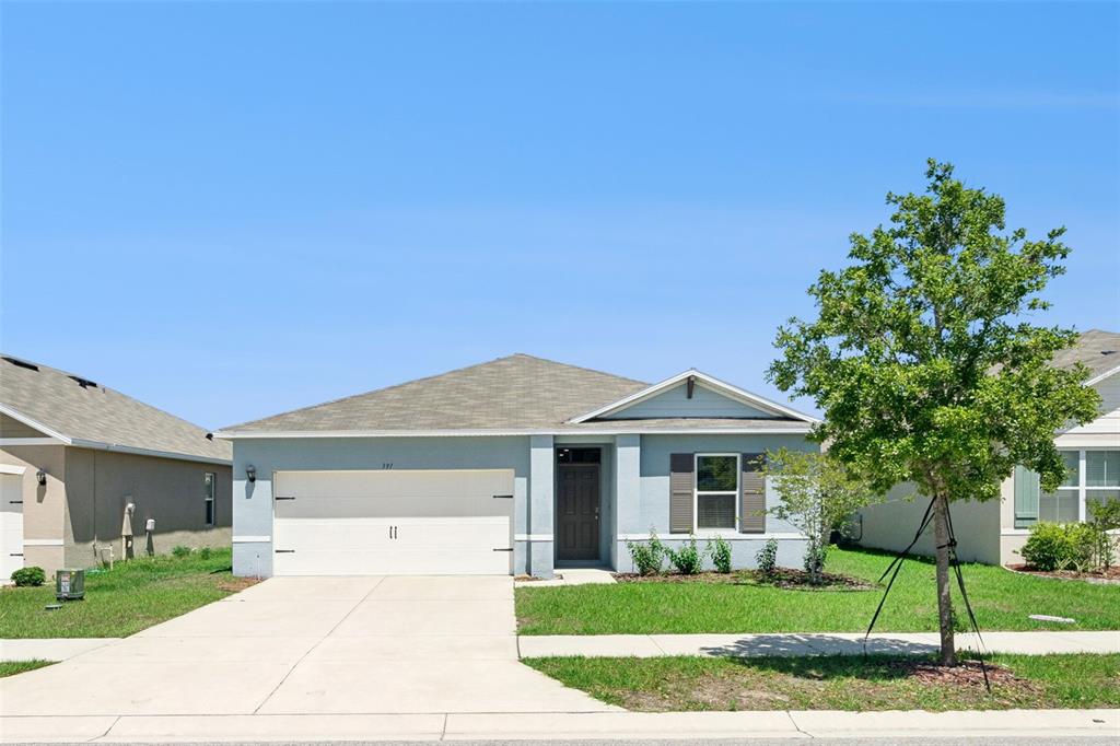 A single-story house with a light blue exterior, a two-car garage, and a front lawn — 391 BOARDWALK AVENUE, HAINES CITY, FL