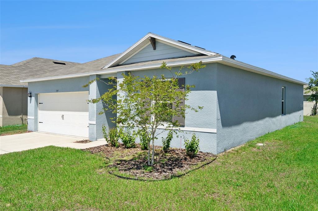 A light blue single-story house with a two-car garage and a small front yard tree — 391 BOARDWALK AVENUE, HAINES CITY, FL