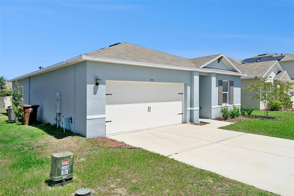 A light blue single-story house features a two-car garage and a concrete driveway — 391 BOARDWALK AVENUE, HAINES CITY, FL