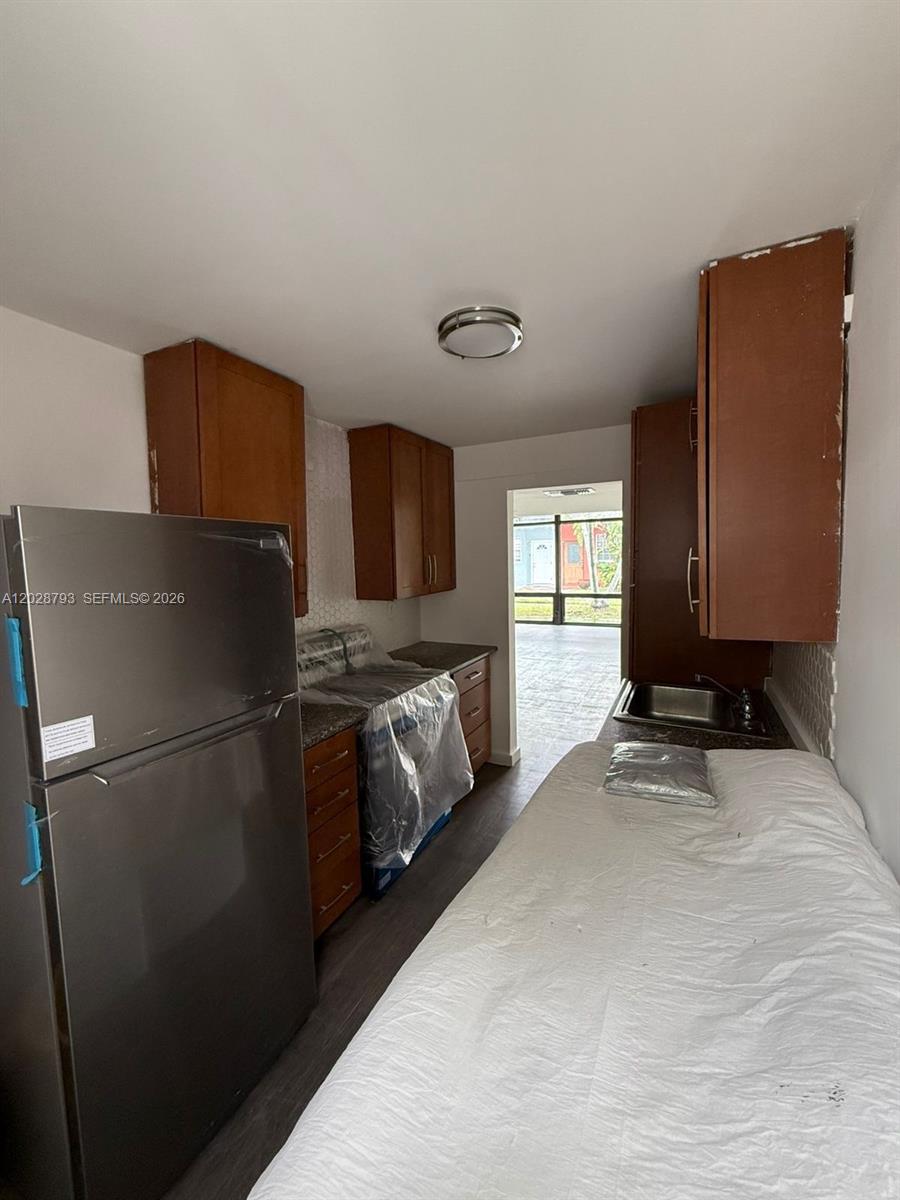 A galley kitchen features dark wood cabinets, stainless steel appliances, and a white countertop — 14310 NE 5th Pl, Miami FL 33161, MIAMI, FL