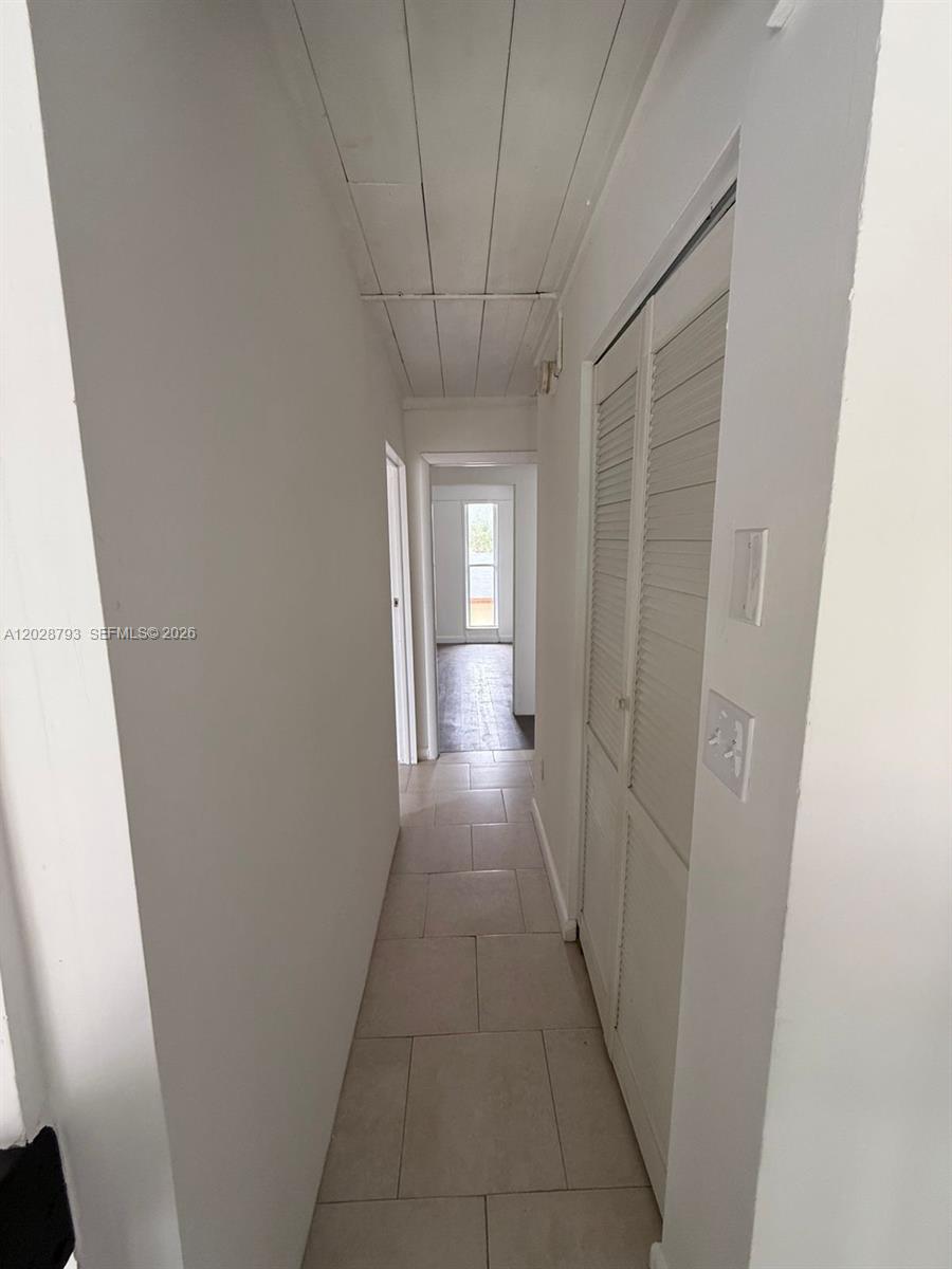 A narrow hallway features white walls, a plank ceiling, and light-colored floor tiles — 14310 NE 5th Pl, Miami FL 33161, MIAMI, FL