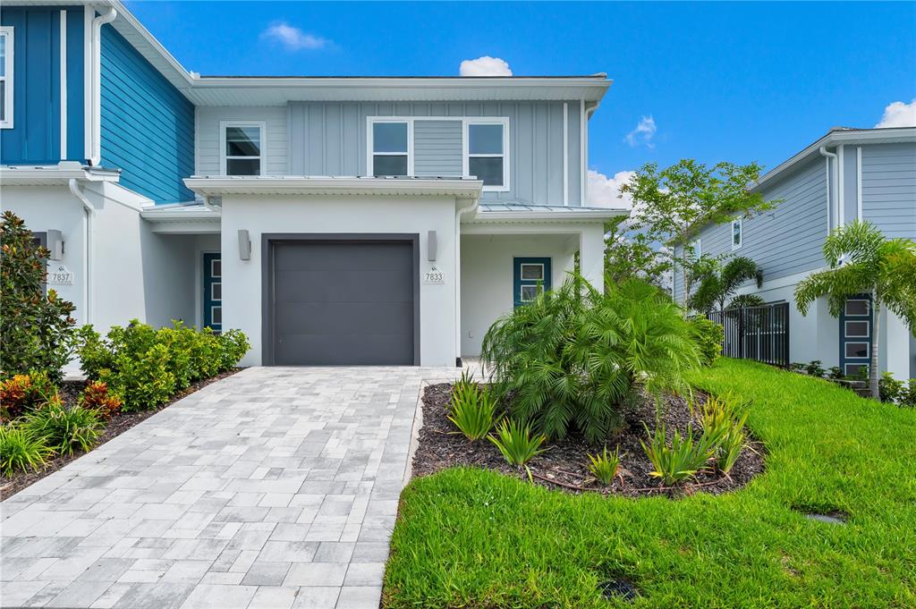 A two-story townhouse exterior features a gray garage, light blue siding, and a paved driveway — 7833 SPECTRUM DRIVE, KISSIMMEE, FL