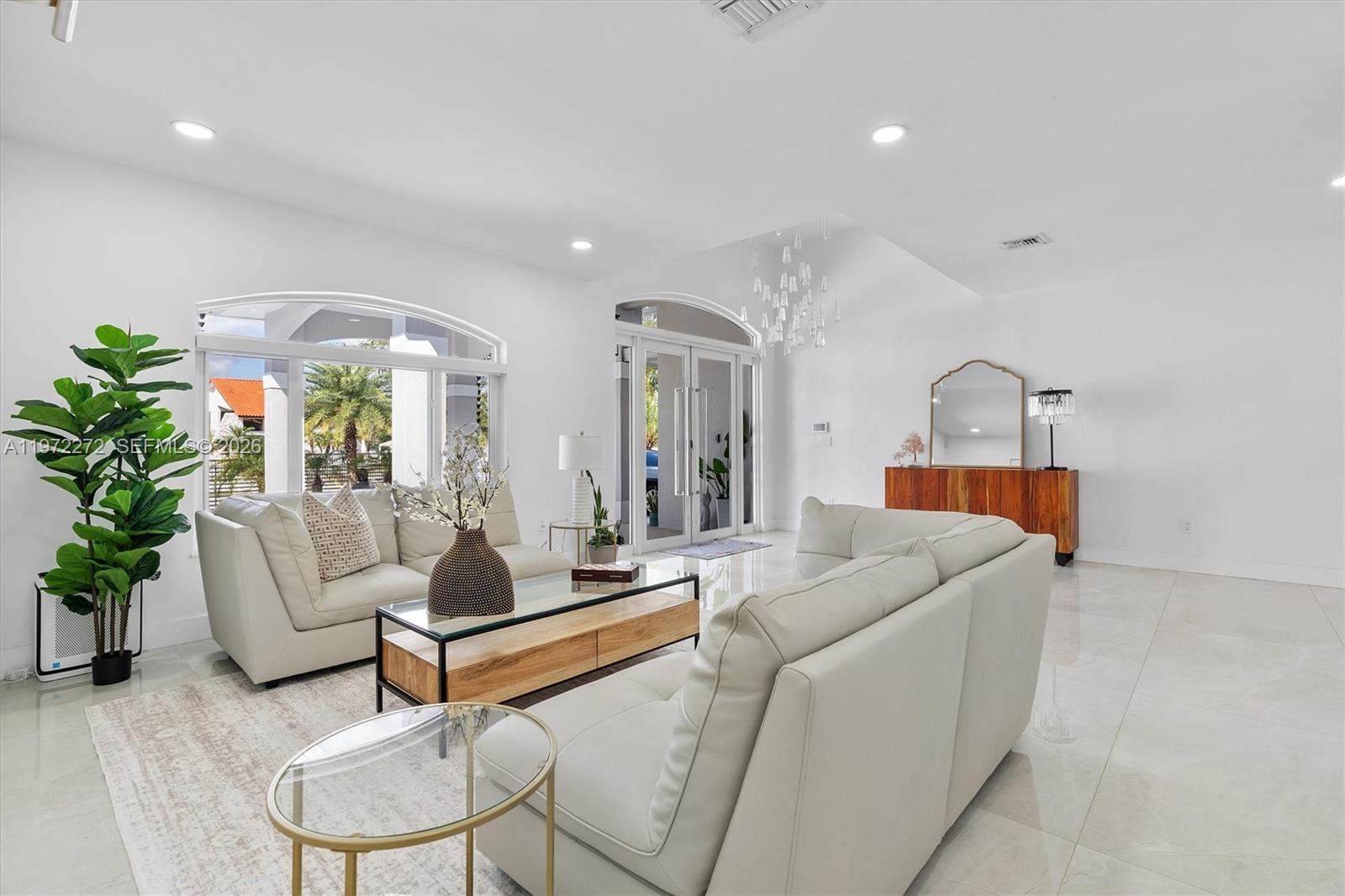 A bright living room features white leather sofas, a glass coffee table, and tile flooring — 135 SW 125th Ave, Miami FL 33184, MIAMI, FL