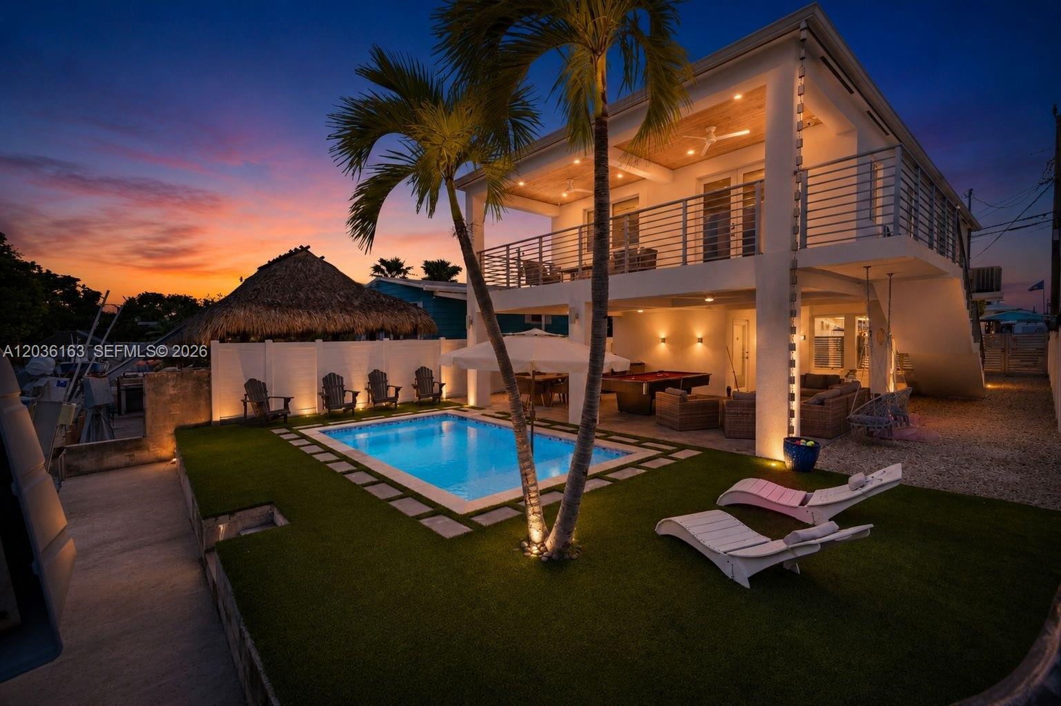 A two-story house with a pool, artificial turf, and a covered patio at sunset — 410 Bowie Ln, Key Largo FL 33037, KEY LARGO, FL