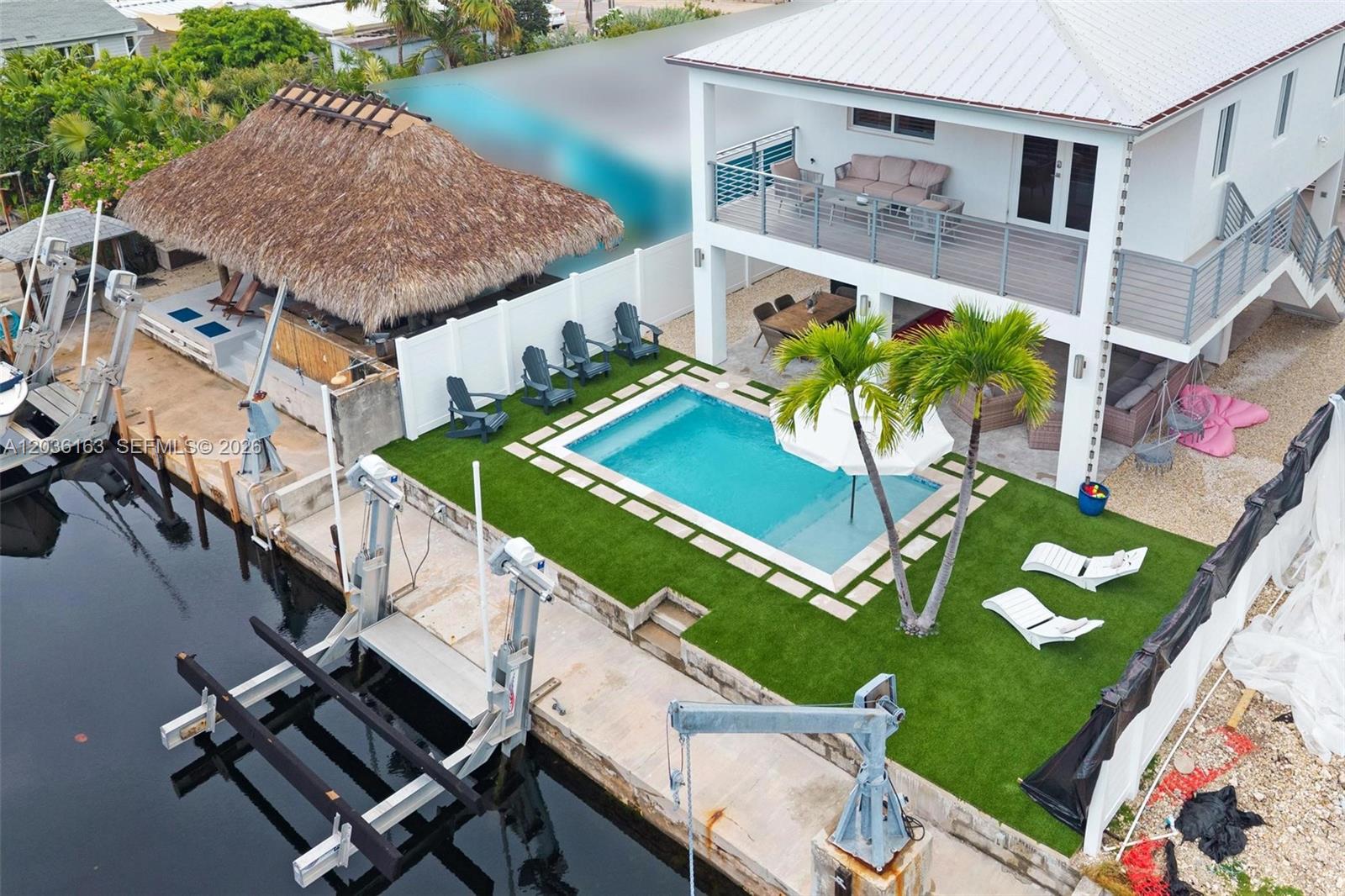 An aerial view shows a waterfront house with a pool, tiki hut, and boat lift — 410 Bowie Ln, Key Largo FL 33037, KEY LARGO, FL