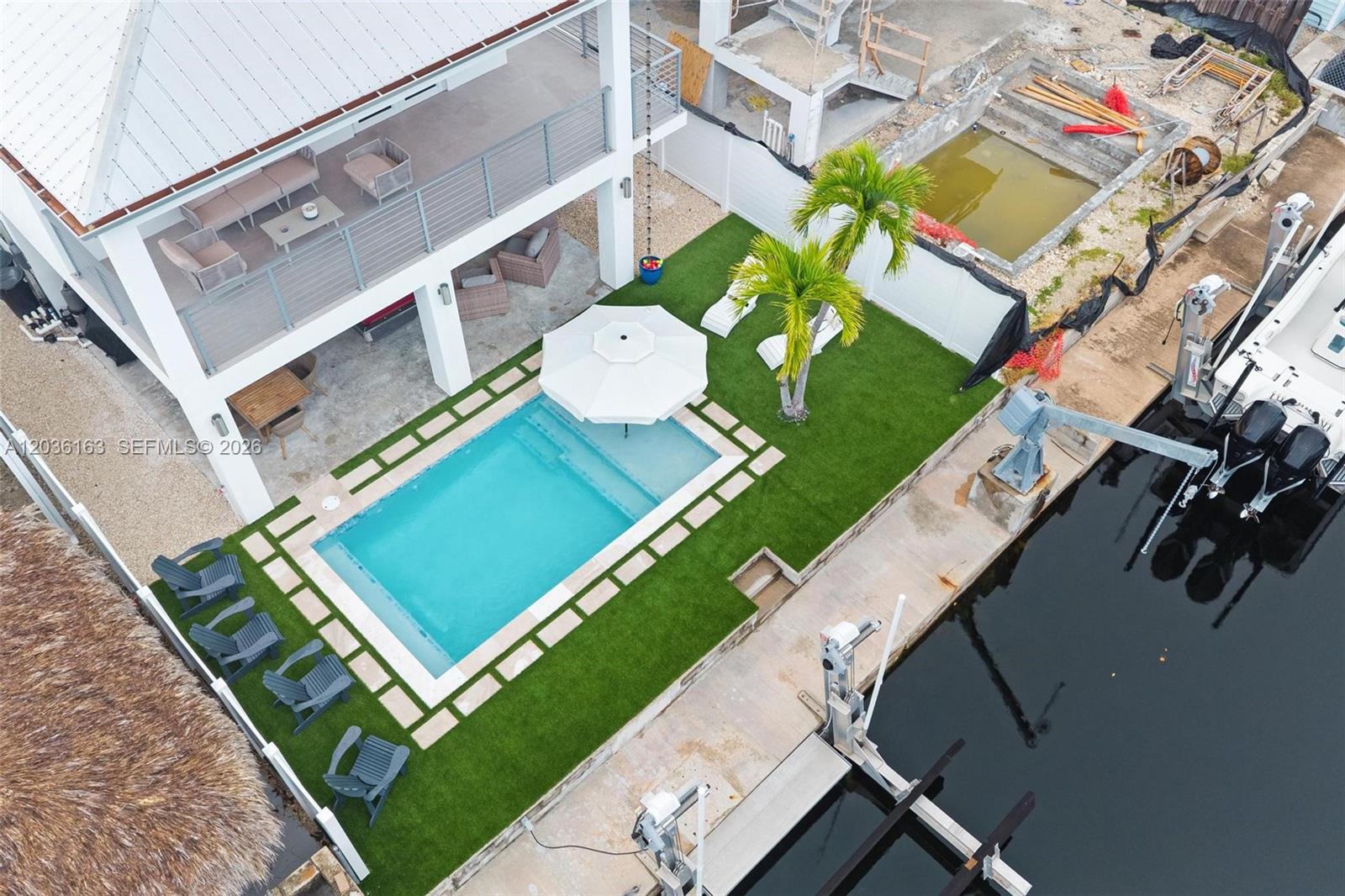 An aerial view shows a house with a pool, patio, and boat dock — 410 Bowie Ln, Key Largo FL 33037, KEY LARGO, FL