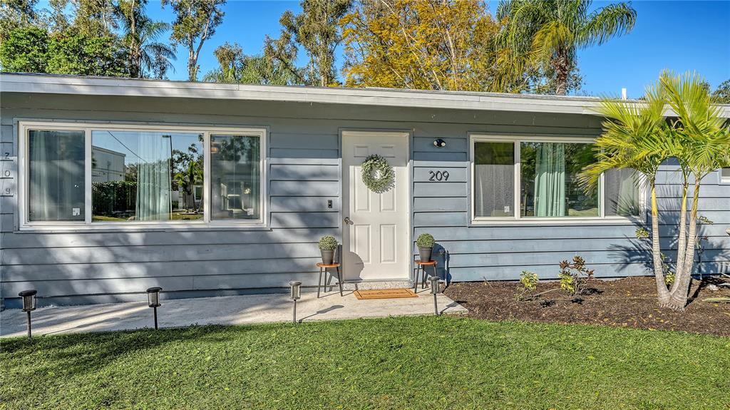 A single-story house with blue horizontal siding, a white front door, and two large windows — 209 BRIGGS COURT, SARASOTA, FL