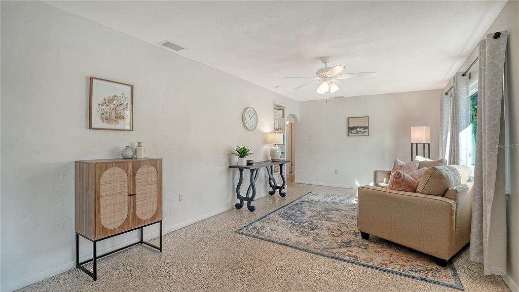 A living room features a beige sofa, a patterned area rug, and a wooden cabinet — 209 BRIGGS COURT, SARASOTA, FL