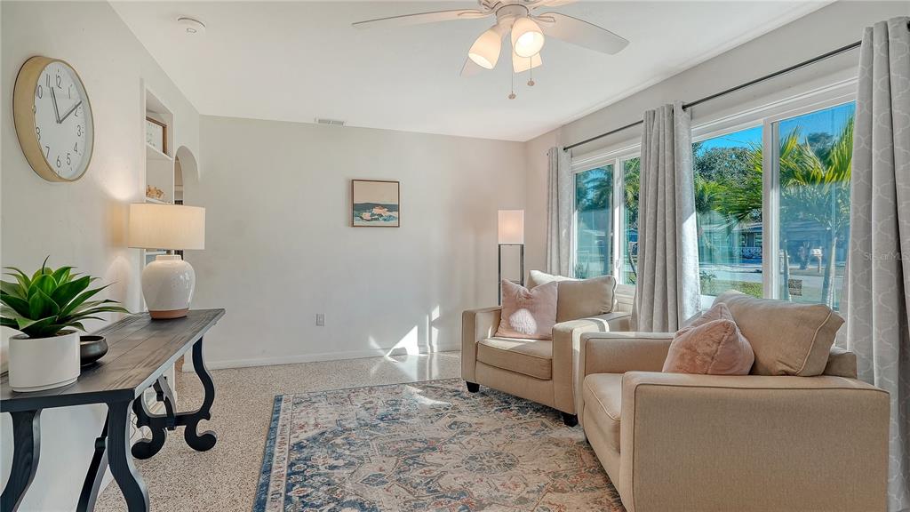 A living room features two beige armchairs, a patterned rug, and a dark wood console table — 209 BRIGGS COURT, SARASOTA, FL