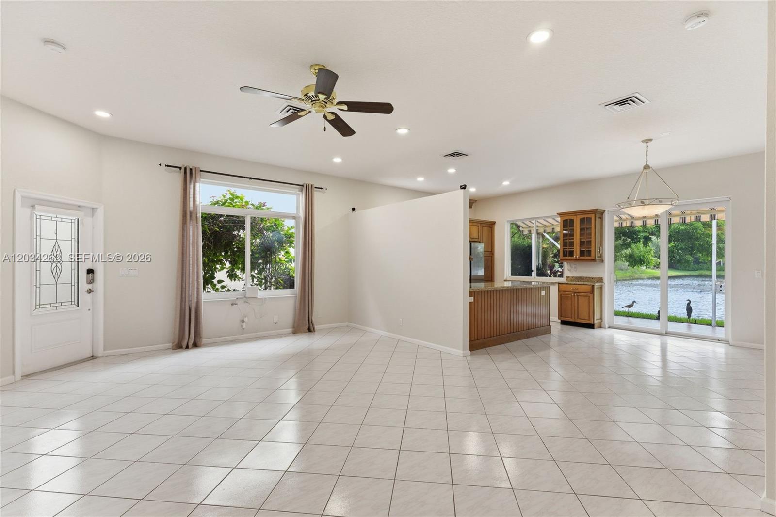 An open-concept living area features tile flooring, a ceiling fan, and a kitchen with cabinetry — 6530 Sandpiper Dr, Coconut Creek FL 33073, COCONUT CREEK, FL