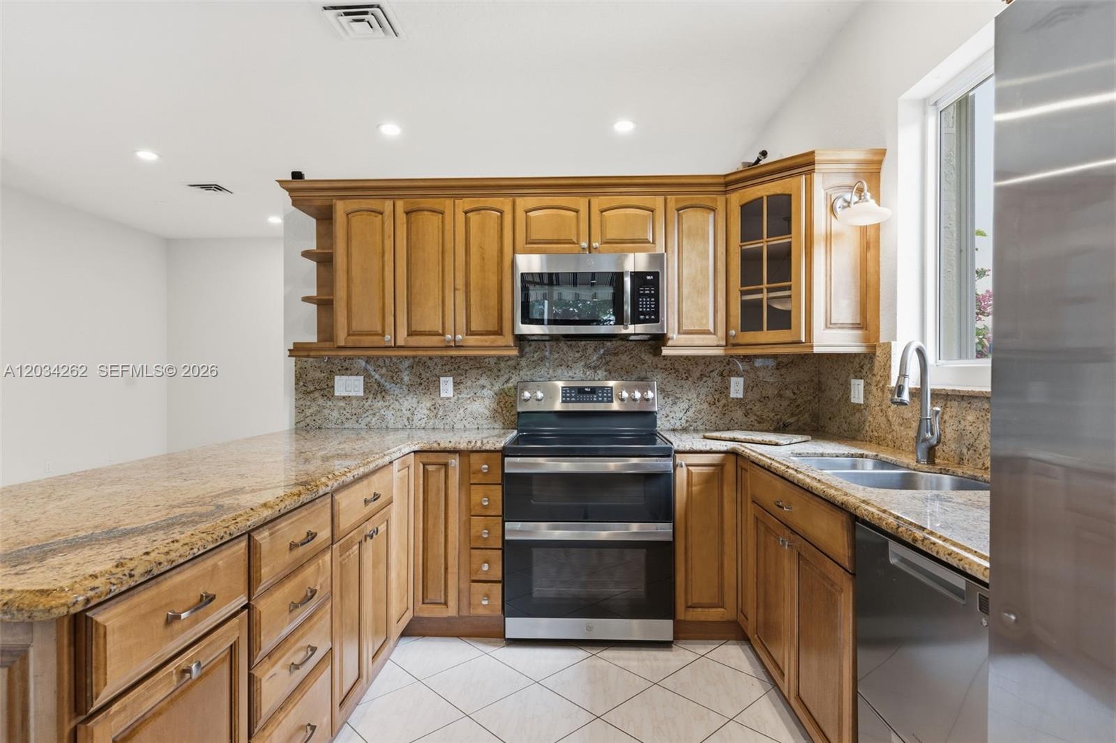 A kitchen features wood cabinets, granite countertops, stainless steel appliances, and tile flooring — 6530 Sandpiper Dr, Coconut Creek FL 33073, COCONUT CREEK, FL