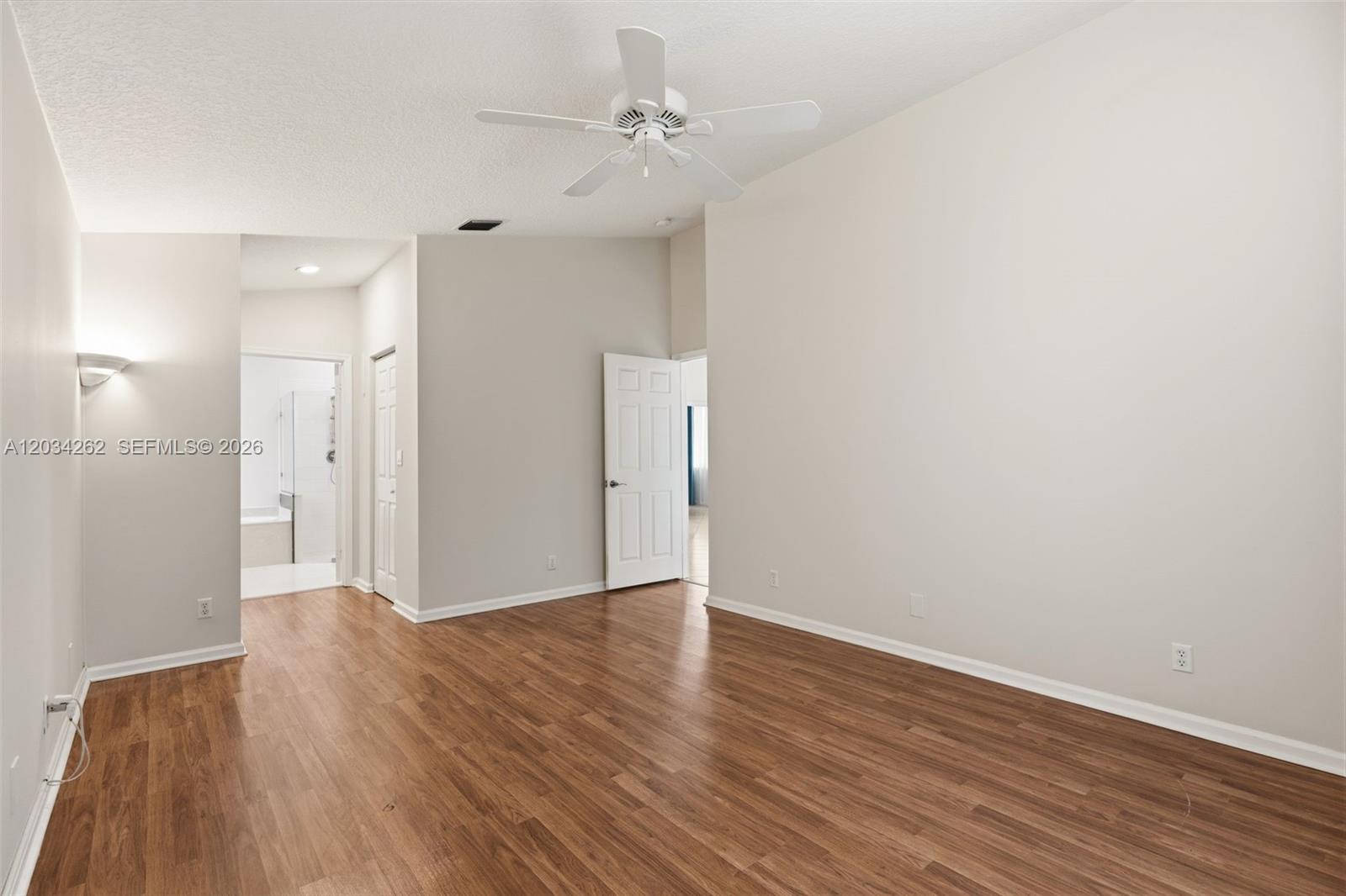 An empty room features wood-look flooring, light-colored walls, a ceiling fan, and an open doorway — 6530 Sandpiper Dr, Coconut Creek FL 33073, COCONUT CREEK, FL