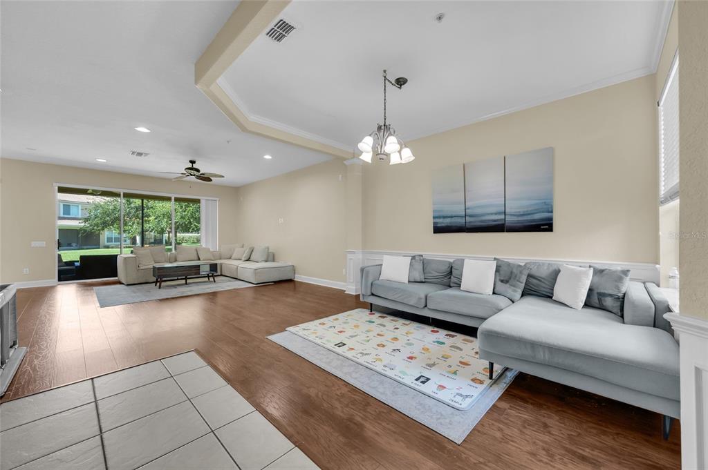 A spacious living room features light-colored walls, wood flooring, two sectionals, and a large rug — 6380 CONEJO TERRACE UNIT 104, ORLANDO, FL