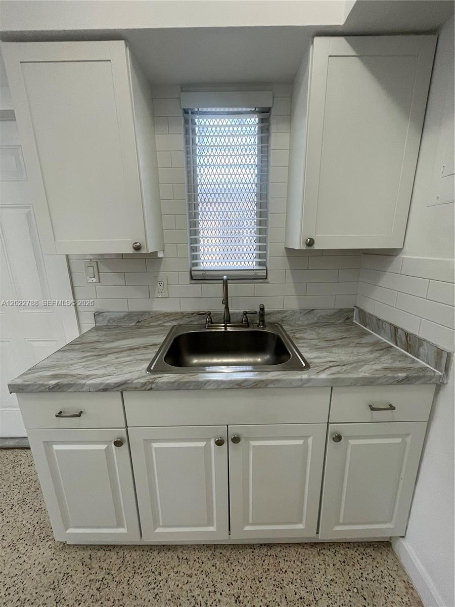 A kitchen sink is centered between white cabinets with a marble-patterned countertop and backsplash — 940 SW 4th ave # 1, Miami FL 33130, MIAMI, FL