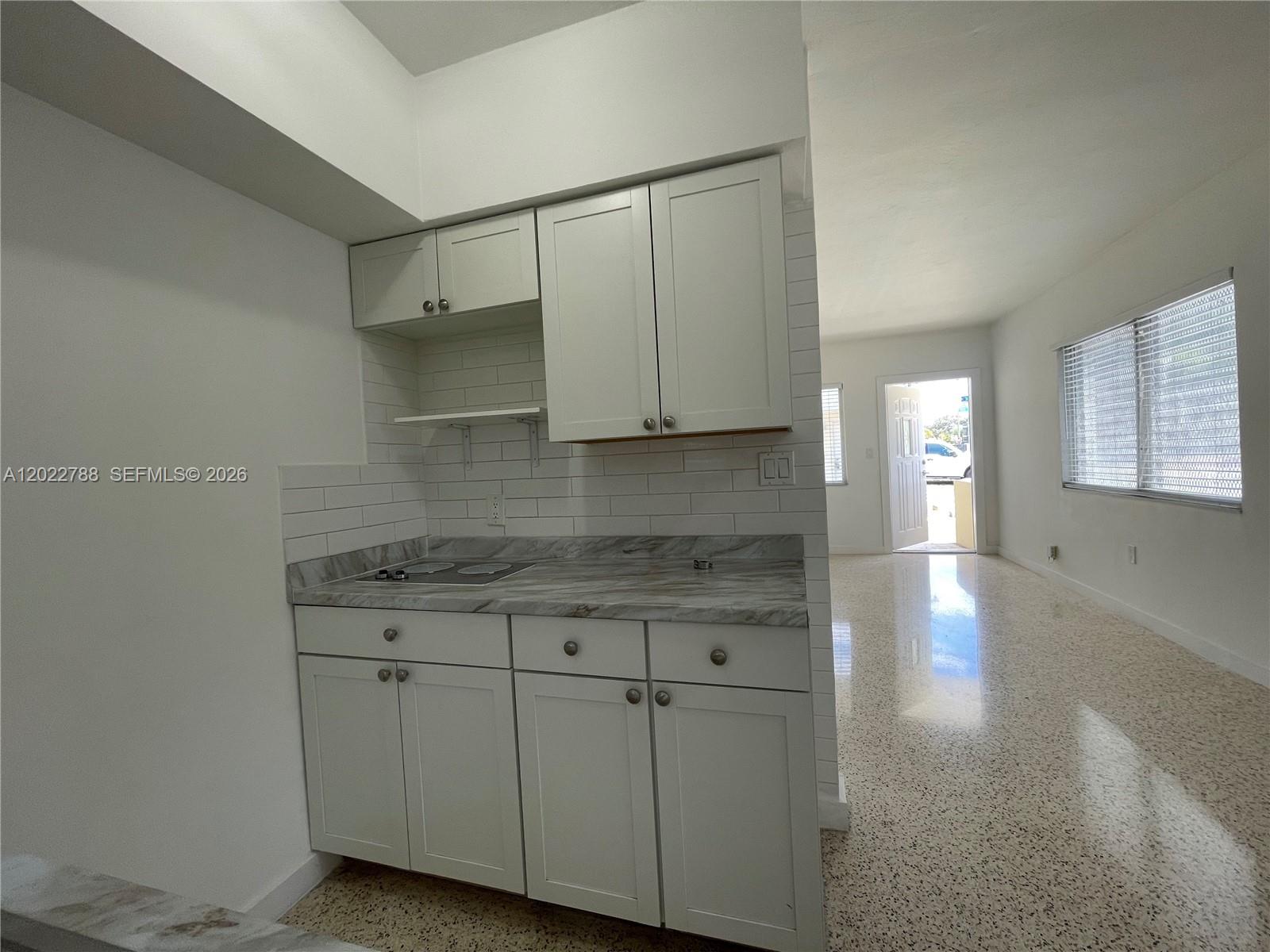 A small kitchen features white cabinets, a marble-patterned countertop, and a white subway tile backsplash — 940 SW 4th ave # 1, Miami FL 33130, MIAMI, FL