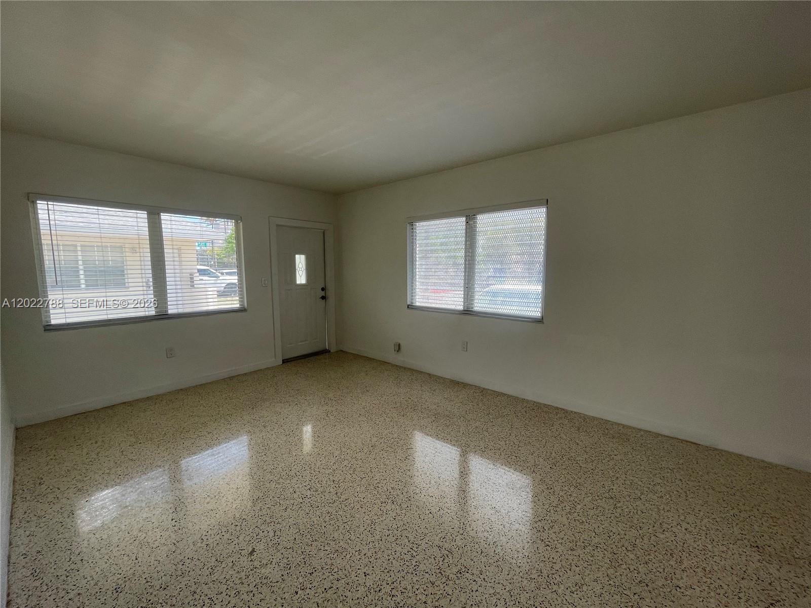 An empty room features white walls, windows with blinds, and a speckled terrazzo floor — 940 SW 4th ave # 1, Miami FL 33130, MIAMI, FL