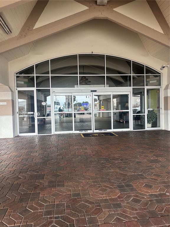 A paved entryway leads to a building entrance with glass sliding doors and arched windows — 2700 N ATLANTIC AVENUE UNIT 415, DAYTONA BEACH, FL