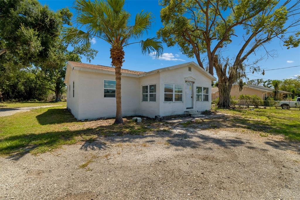 A single-story white house with a palm tree in front and a gravel driveway — 1611 E SHELL POINT ROAD, RUSKIN, FL